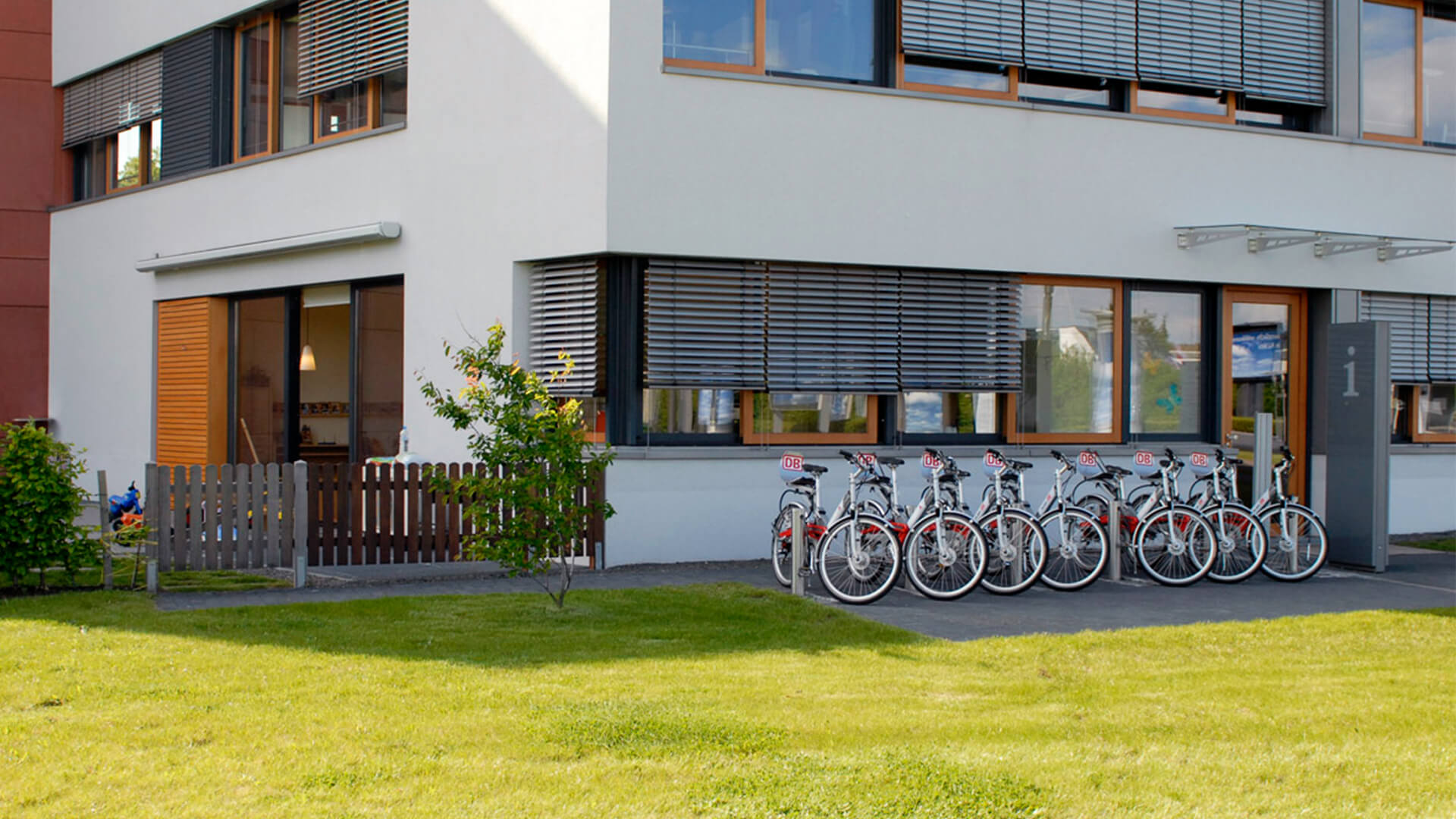 Fahrräder vor dem Kindergarten mit moderner Außenfront, Wiese und Sonnenschein