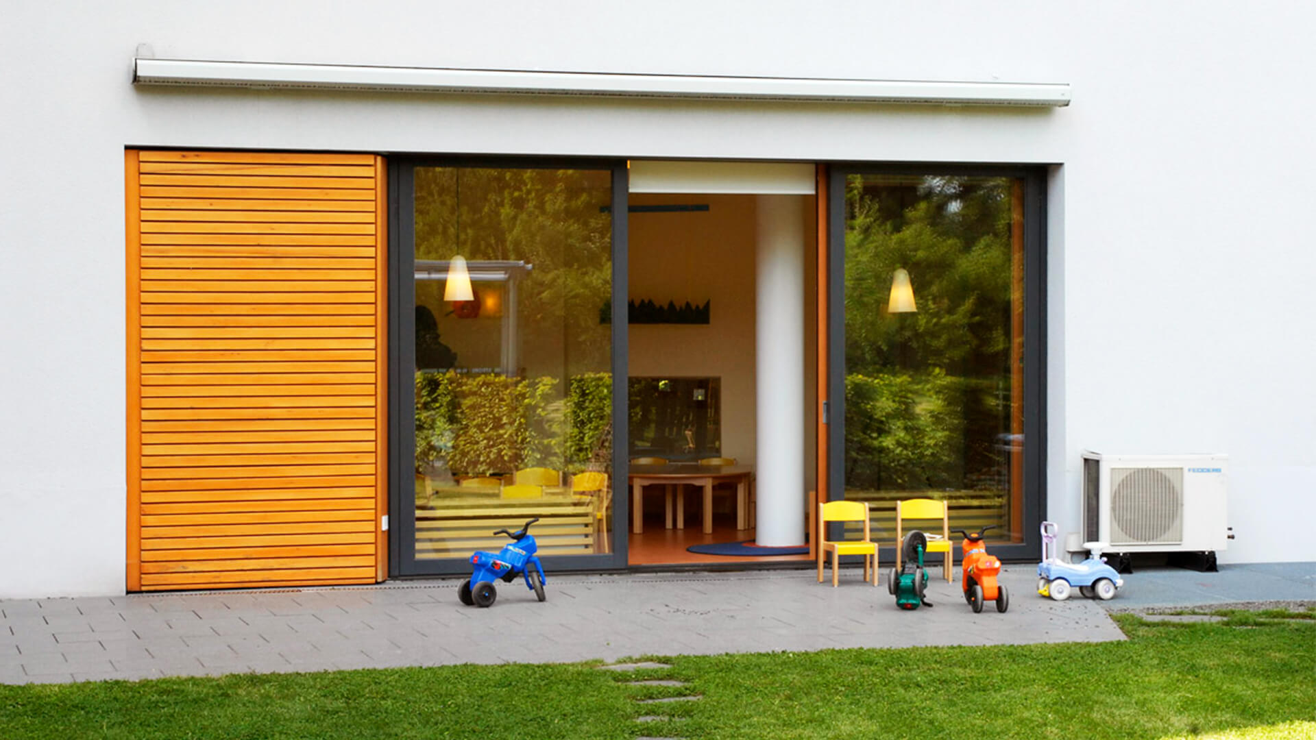 Terrasse des Betriebskindergarten in Köln - mit Bobbycars und Wiese