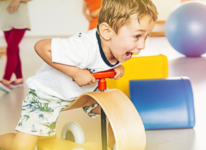 Kind auf Holz-Bobbycar beim aktiven Spiel in der Kindertagesstätte