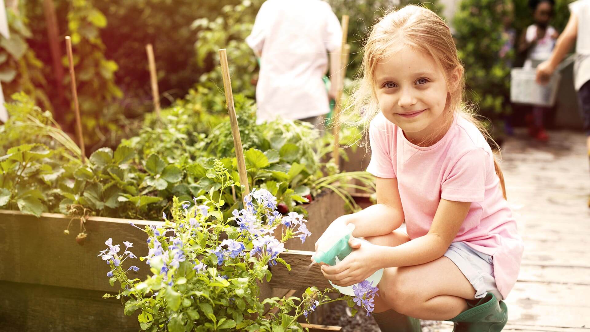 Erfahrungen sammeln beim gemeinsamen pflegen des Blumen- und Erdbeerbeets an der frischen Luft