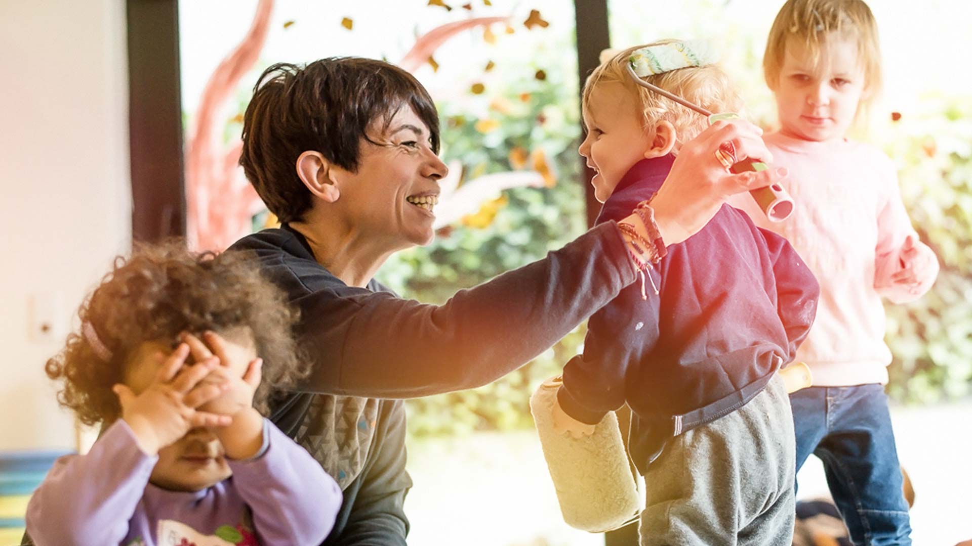 Pädagogischer Ansatz Kita Betreuerin spielt mit drei Kindern